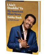 Product Description: AUTOGRAPHED copy of I Ain't Studdin' Ya: My American Blues Storybook by Bobby Rush.</br></br>In I Ain't Studdin Ya: My American Blues Story (Hachette Books), Blues Hall of Famer, Blues Music Award and GRAMMY® Winner Bobby Rush gives readers intimate access into his life and career like never before. Born Emmett Ellis, Jr., in Louisiana to a Black father and a mother who passed as white, Rush spent his childhood days picking cotton with his family and making music with syrup cans, broomsticks and hay wire. Rush transports readers into the Deep South of the 1930s and 1940s, reflecting on family values, racial tensions, and the significant contributions Black Americans made to music culture.</br></br>Rush’s early experiences, particularly the unshakable bond he shared with his father, would go on to influence his long and noteworthy career that rose out of the Chicago blues scene. Throughout the years, Rush befriended and performed alongside fellow music legends, including Muddy Waters, B.B. King, and Little Walter. While opening for the likes of Tina Turner and Ray Charles, he bought a hot dog stand and ran his own barbeque joint to make ends meet. When faced with personal tragedy, multiple near-death experiences, and incarceration, Rush relied on his music and steadfast Baptist faith, never losing his sense of determination, passion for bringing others joy, and love of the music.</br></br>I Ain't Studin' Yagives readers a behind-the-scenes look into Rush’s life as he:</br>-Sneaks into juke joints wearing a fake mustache at age 12</br>-Graduates from touring with a minstrel show to becoming a Chitlin’ Circuit favorite</br>-Loses $30,000 and learns a lesson of trust during a business deal gone wrong with James Brown</br>-Records hits like “Chicken Heads,” “Sue,” and the Grammy-winning album “Porcupine Meat”</br>-Becomes the first blues musician to perform at the Great Wall of China</br>-Analyzes the evolution of blues as a reflection of the Black experience in America</br> I Ain't Studdin' Ya: My American Blues Story Book